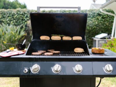 Outdoor barbecue grill with burgers and buns, perfect for summer cooking.