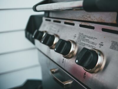 Detailed view of barbecue grill controls, showcasing knobs and stainless steel surface.
