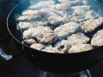 Close-up of fish fillets sizzling on a barbecue grill outdoors, exuding a smoky aroma.