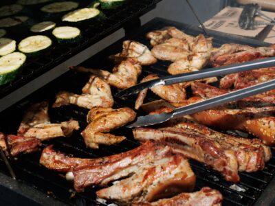 Delicious barbecue chicken and zucchini grilling outdoors on a sunny day.
