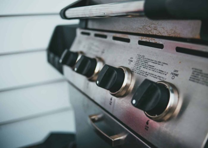 Detailed view of barbecue grill controls, showcasing knobs and stainless steel surface.