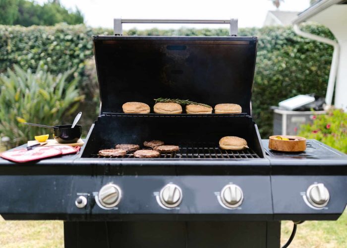 Outdoor barbecue grill with burgers and buns, perfect for summer cooking.
