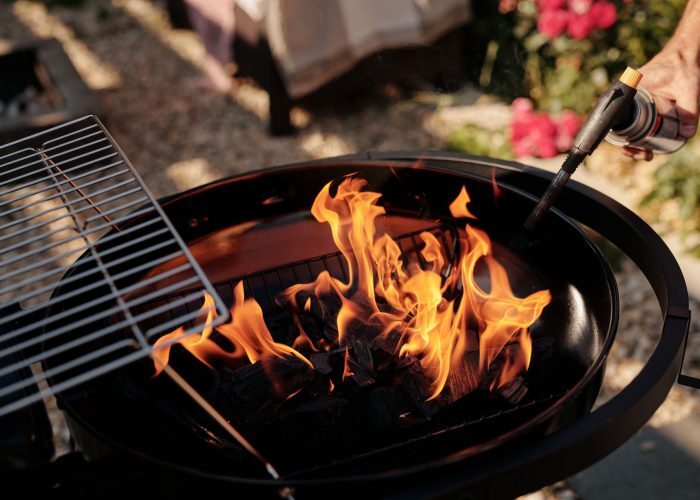 A charcoal grill ignited with flames using a torch. Perfect for outdoor barbecues. — carbón o eléctrica: cuál te conviene